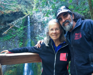 Woman and man smiling in front of waterfall