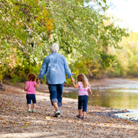 a grandmother walking by the river with two grandkids