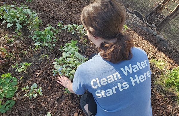 woman gardening; shirt says, "clean water starts here"