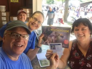 Four people smiling with Weatherguide calendar at the Minnesota State Fair
