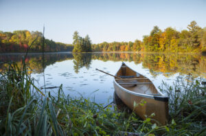 photo of a canoe on a lake with trees in the background