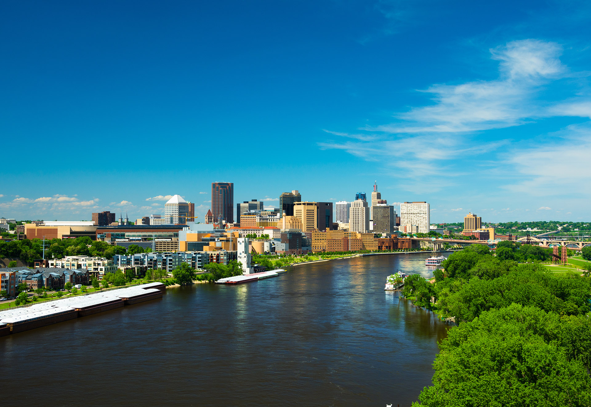 Saint Paul downtown skyline with the Mississippi River and trees in the foreground, wide angle view.